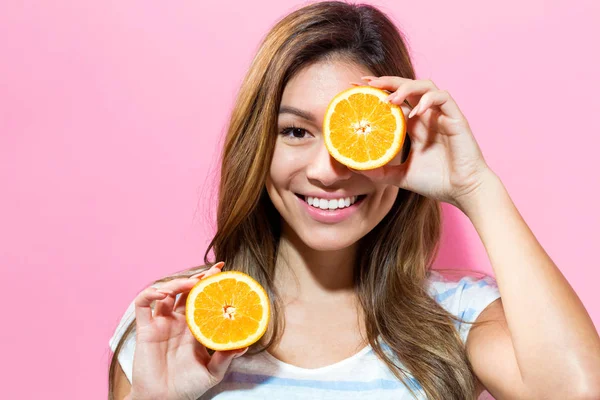 Jovem feliz segurando laranjas metades — Fotografia de Stock