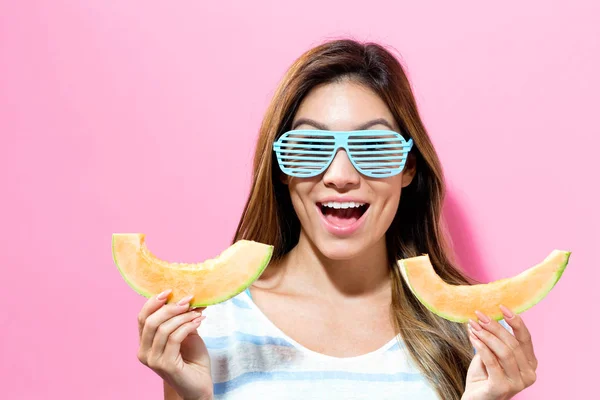 Happy young woman holding slices of cantaloupe — Stock Photo, Image