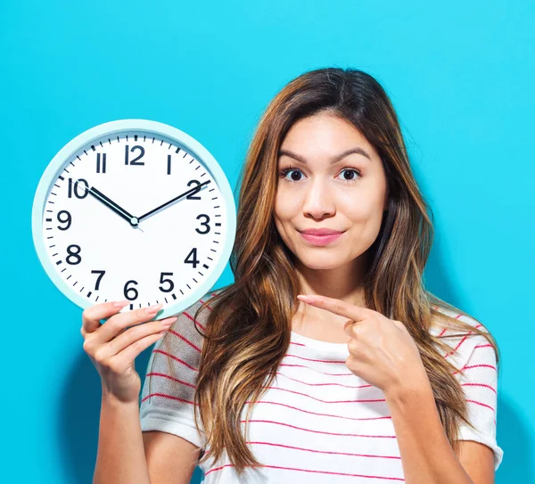 Mujer joven sosteniendo un reloj — Foto de Stock