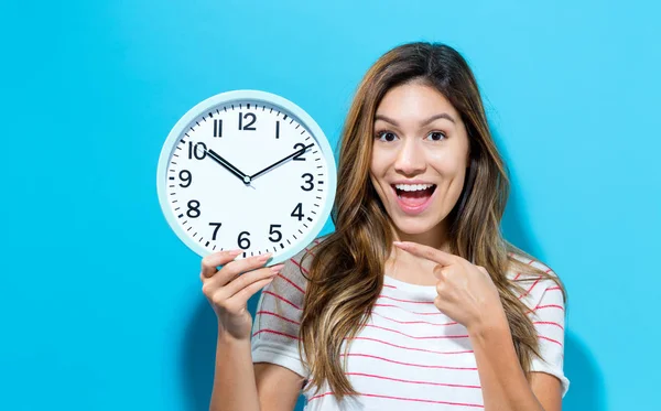 Mujer joven sosteniendo un reloj — Foto de Stock