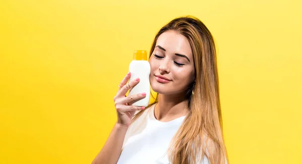 Mujer joven una botella de bloqueador solar — Foto de Stock