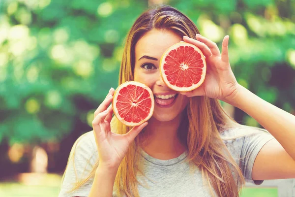Happy young woman holding grapefruit — Stock Photo, Image