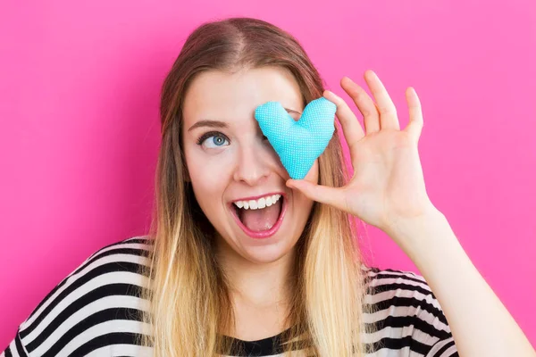 Happy young woman holding a heart cushion — Stock Photo, Image