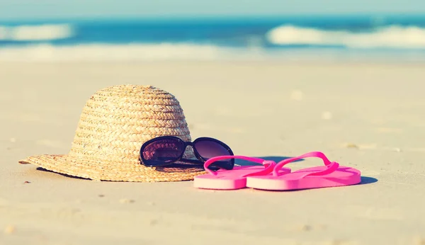 Slaměný klobouk a sluneční brýle na na pláži — Stock fotografie