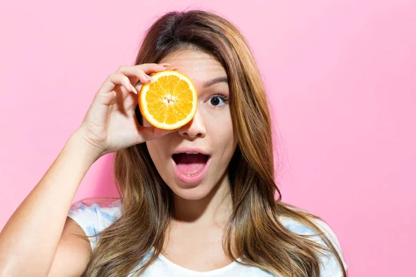 Mutlu genç bir kadın tutarak turuncu — Stok fotoğraf