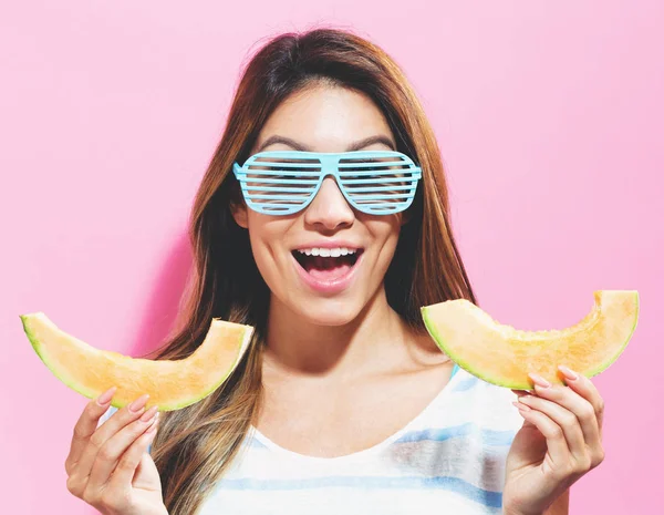 Happy young woman holding slices of cantaloupe — Stock Photo, Image