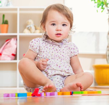 Onun oyuncakları ile oynarken mutlu yürümeye başlayan çocuk kız 