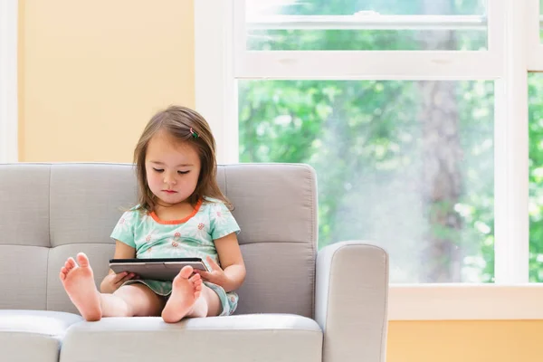 Menina criança feliz brincando com seu computador tablet — Fotografia de Stock