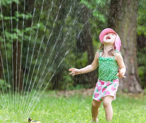 Happy toddler girl playing in a sprinkler — Stock Photo, Image