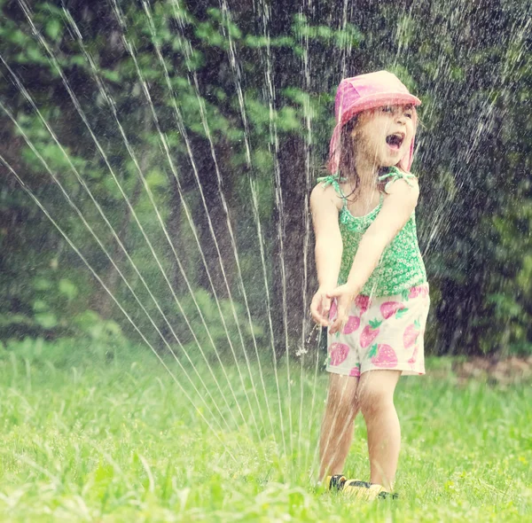 スプリンクラーで遊ぶ幸せな幼児の女の子 — ストック写真