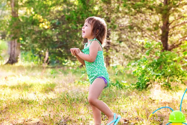 Feliz niña jugando con aspersor — Foto de Stock
