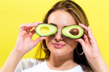 Avokado yarısını tutan mutlu genç kadın