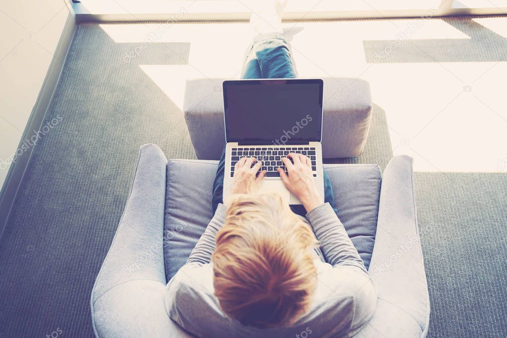 Man on a laptop in bright window lit room