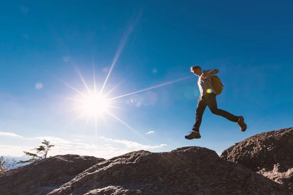 Man jumping over gap on mountain hike — Stock Photo, Image