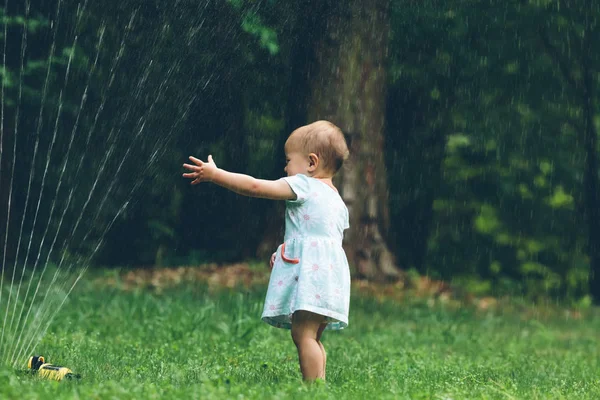 Ευχαρίστως toddler κορίτσι παίζει σε έναν ψεκαστήρα — Φωτογραφία Αρχείου