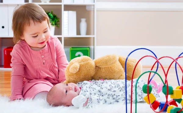 Happy toddler girl playing with her baby sibling — Stock Photo, Image