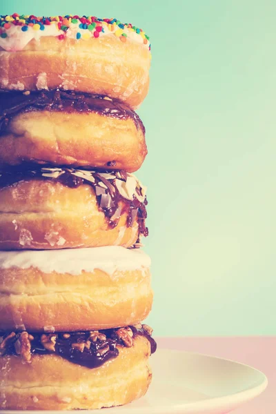 Pastel pembe ve mavi arka plan üzerinde çeşitli çörekler yığını