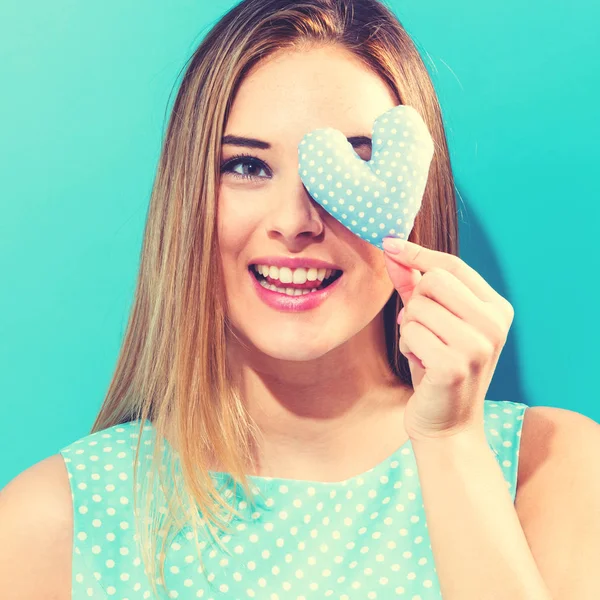 Happy young woman holding heart cushion — Stock Photo, Image