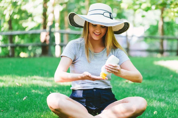 Junge Frau eine Flasche Sonnencreme draußen — Stockfoto