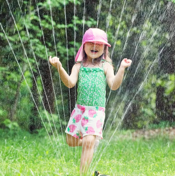 Feliz niña jugando en un aspersor —  Fotos de Stock