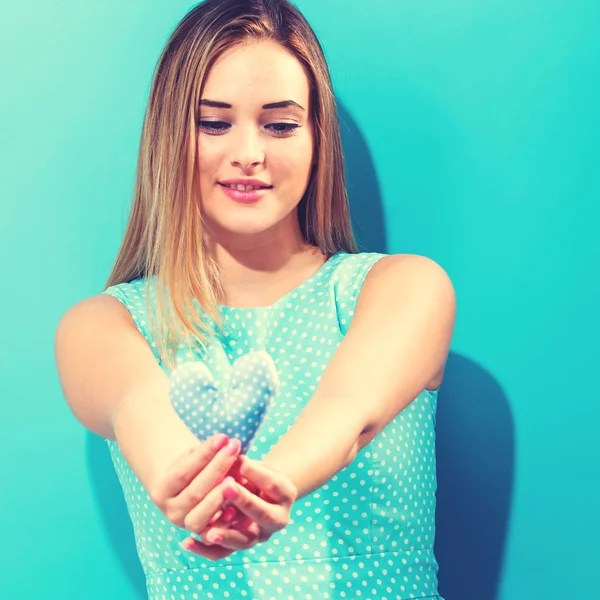 Happy young woman holding heart cushion — Stock Photo, Image