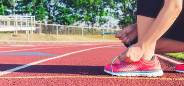 Kadın koşucu ayakkabıları bir stadyum yolda bağlama