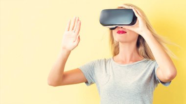 Sanal gerçeklik kulaklığı kullanan genç bir kadın.