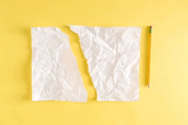Trozo de papel roto y un lápiz sobre amarillo — Foto de Stock
