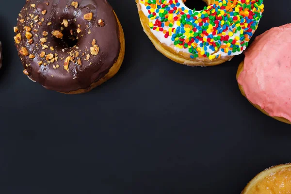 Geassorteerde donuts op een zwarte achtergrond — Stockfoto