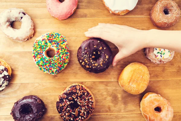 Person placing assorted colorful donuts — Stock Photo, Image
