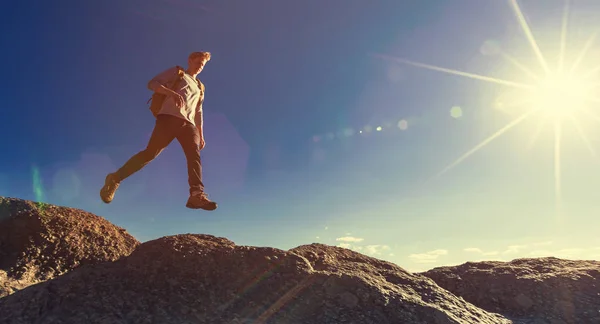 Man jumping over gap on mountain hike — Stock Photo, Image