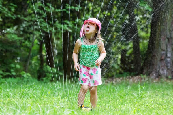 Kleuter meisje spelen in een sprinkler — Stockfoto
