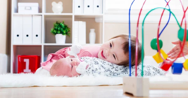 Toddler girl playing with her baby sibling — Stock Photo, Image