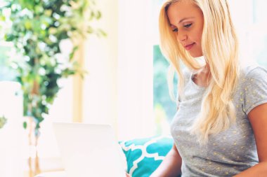 Dizüstü bilgisayarını kullanan mutlu genç kadın.