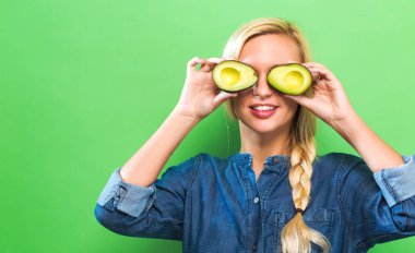 Avokado yarısını tutan mutlu genç kadın 