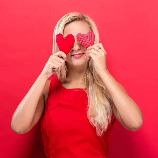 Happy young woman holding heart cushions — Stock Photo, Image