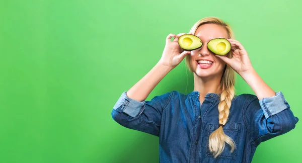 Щаслива молода жінка тримає половинки авокадо — стокове фото