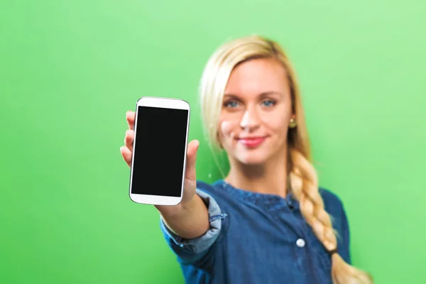 Ung kvinna håller ut en mobiltelefon — Stockfoto