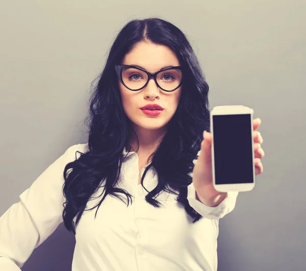 Ung kvinna håller ut en mobiltelefon — Stockfoto