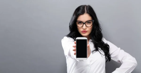 Молода жінка тримає мобільний телефон — стокове фото