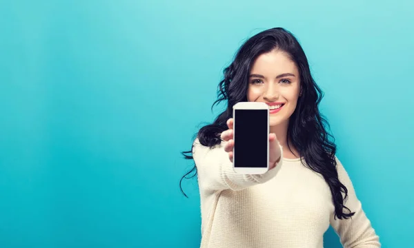 Ung kvinna håller ut en mobiltelefon — Stockfoto
