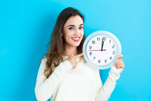 Woman holding clock showing nearly 12 — Stock Photo, Image