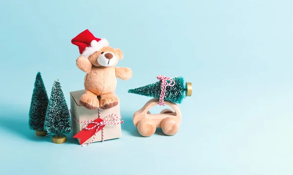 Osito de peluche en un sombrero de Santa con una caja de regalo y árboles de Navidad — Foto de Stock
