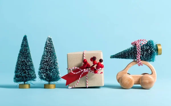 Miniaturní dřevěné auto přepravující vánoční stromeček — Stock fotografie