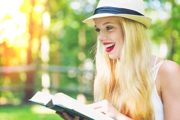 Ung kvinna läser en bok utanför — Stockfoto