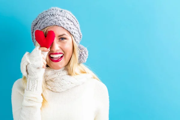 Happy young woman holding a heart cushion — Stock Photo, Image