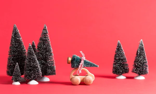 Miniature wooden car carrying a Christmas tree — Stock Photo, Image