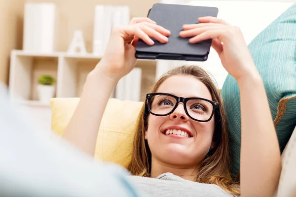 Mutlu genç kadın onun kanepede bir e-kitap okuma — Stok fotoğraf
