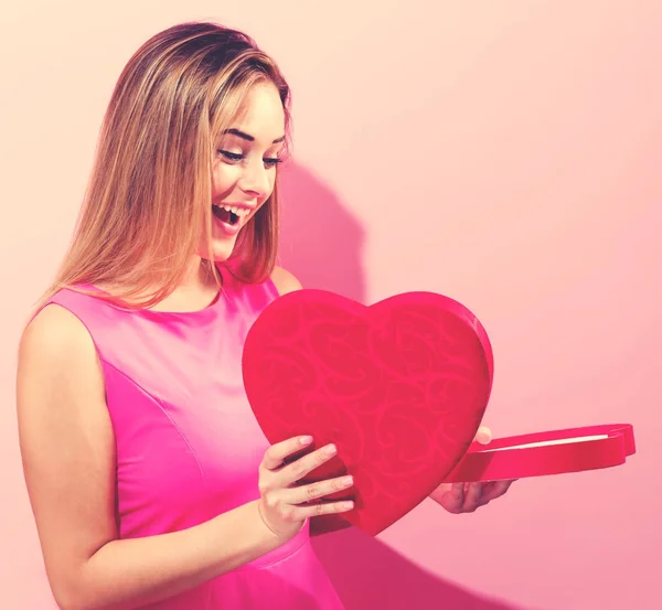 快乐的年轻女子捧着心脏形状的盒子 — 图库照片