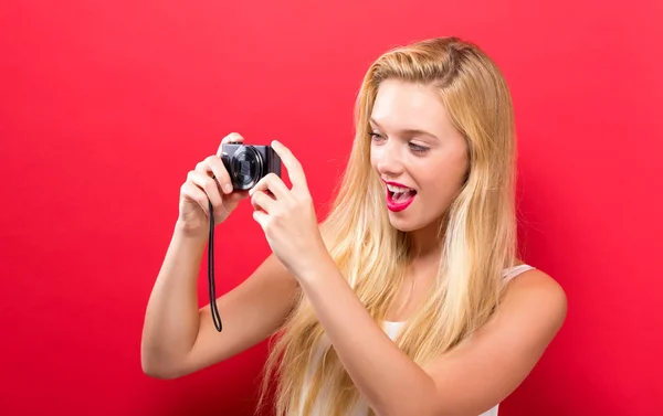 Jeune femme tenant une caméra compacte — Photo